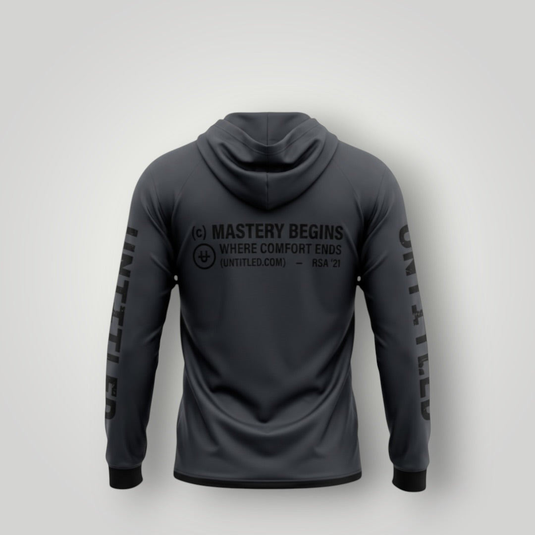 A dark gray hooded long-sleeve shirt shown from the back, featuring black printed text and logos including 'MASTERY BEGINS' and 'WHERE COMFORT ENDS' on the back, with 'UNITED' printed down both sleeves, set against a light gray background.